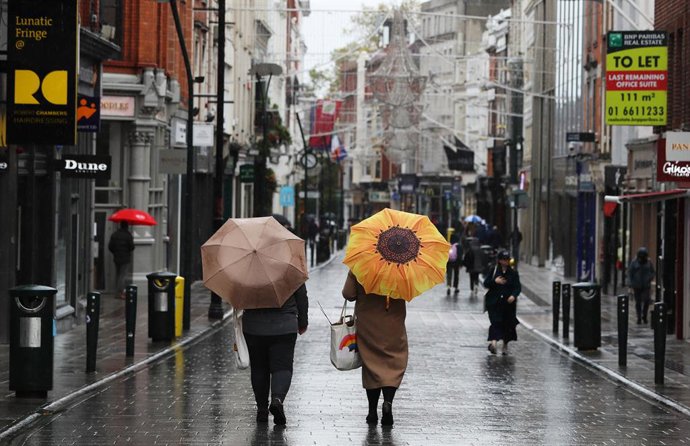 Archivo - 11 November 2020, Ireland, Dublin: People hold umbrellas as they walk down a quiet Grafton street on a rainy day in Dublin's city centre. Photo: Brian Lawless/PA Wire/dpa