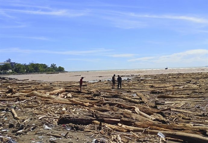 November 29, 2025, Padang, West Sumatra, Indonesia: People stand among piles of logs on Air Tawar Beach, Padang, West Sumatra, Indonesia. The logs have piled up along Padang Beach in the aftermath of flash floods. The death toll from floods and landslides