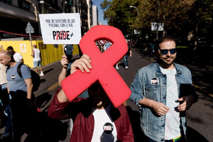 Archivo - Manifestantes portan un lazo rojo y pancarta con lema 'Por los derechos de las personas con VIH' durante la Cuarta Marcha Positiva organizada por Pride Positivo, a 18 de octubre de 2025, en Madrid (España).
