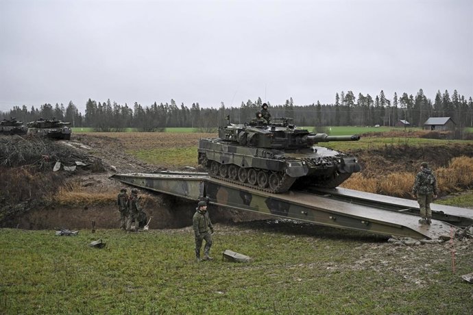 01 December 2025, Finland, Orimattila: Leopard II main battle tanks cross a trench on a bridge built by a bridge tank during the media day of the army's main regional war exercise "Lively Sentry 25" in Artjarvi. During the exercise, a tank company attacks