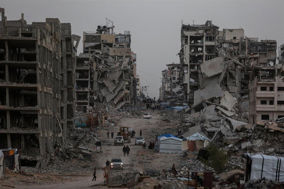 Palestinos entre edificios destruidos en la ciudad de Gaza por la ofensiva militar de Israel contra la Franja tras los ataques del 7 de octubre de 2023 (archivo)