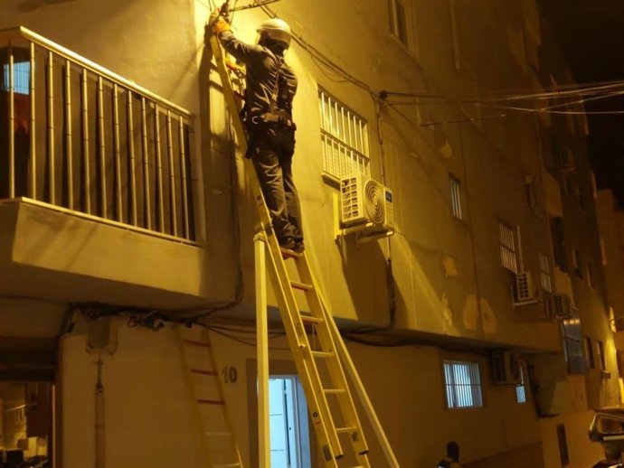 Un técnico retira un enganche irregular a la red eléctrica durante la intervención policial.