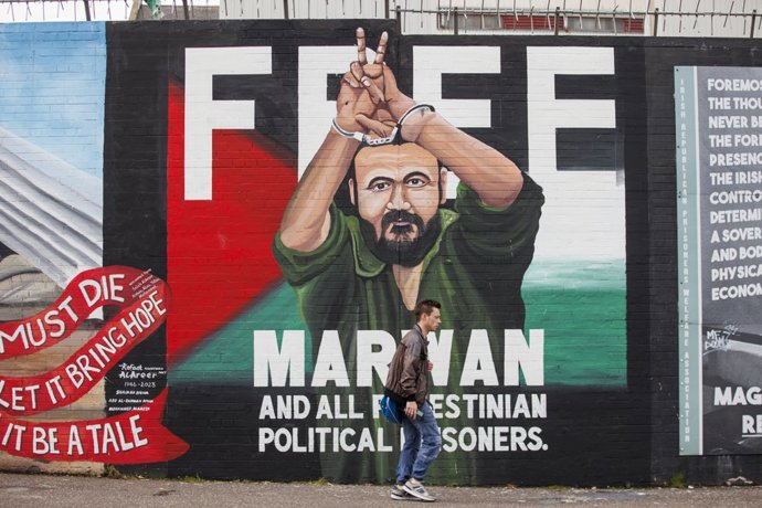 19 September 2025, United Kingdom, Belfast: A man walks past a mural of Palestinian political leader Marwan Barghouti, at the International Wall in Belfast, which was commissioned by Mothers Against Genocide and painted by mural artist Marty Lyons.