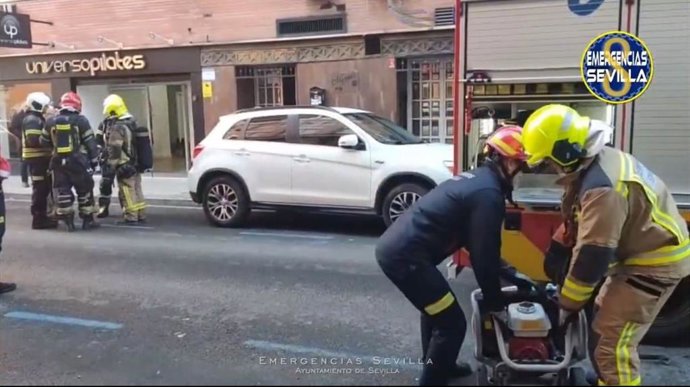 Bomberos durante la actuación en un incendio en un local de la calle Santo Domingo de la Calzada de Sevilla.
