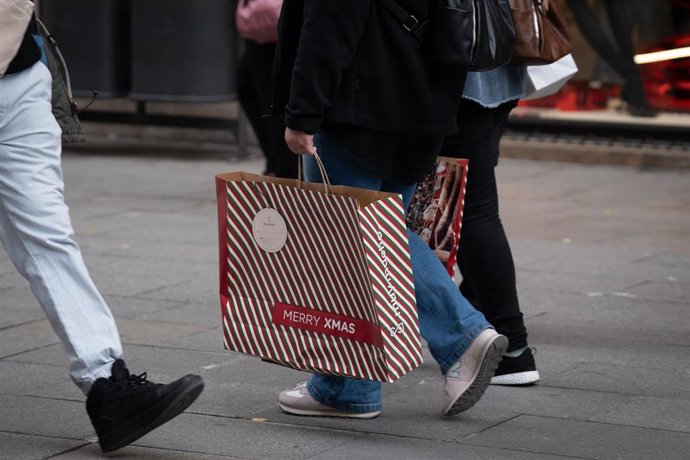 Archivo - Una persona sujeta bolsas con compras durante la campaña de Navidad.