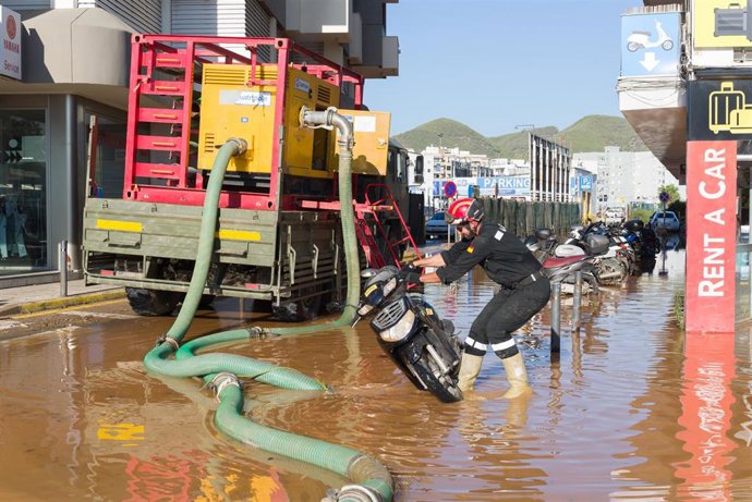 Archivo - Un militar de la UME aparta una moto de una calle anegada de agua tras las lluvias en Ibiza.