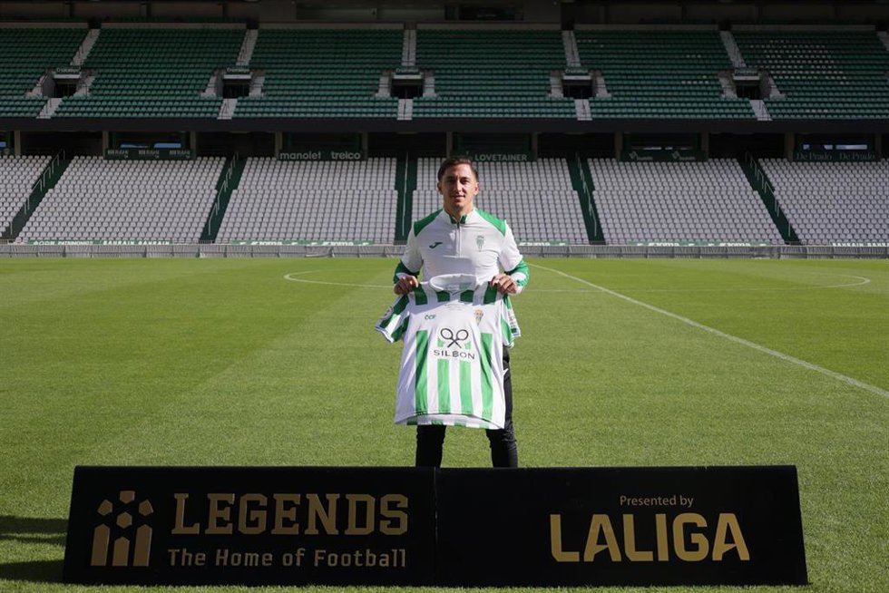 El jugador del Córdoba CF Cristian Carracedo posando junto a la camiseta del ascenso a LaLiga Hypermotion  en el estadio Nuevo Arcángel.