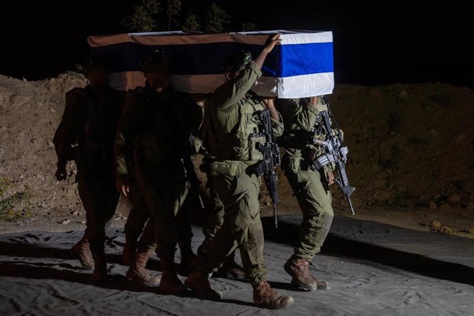 Soldados das Forças de Defesa de Israel (IDF) carregam um caixão contendo os restos mortais de um refém morto entregue pelo Hamas.