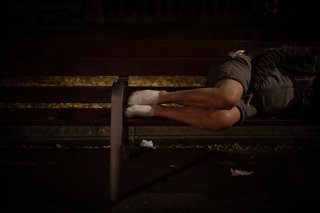 Archivo - Un hombre duerme sobre un banco.