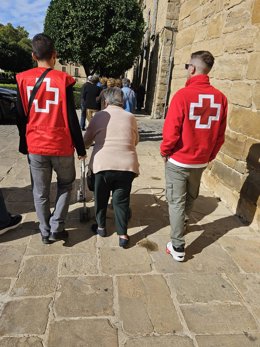 Archivo - Dos voluntarios de Cruz Roja acompaña a una mujer mayor.