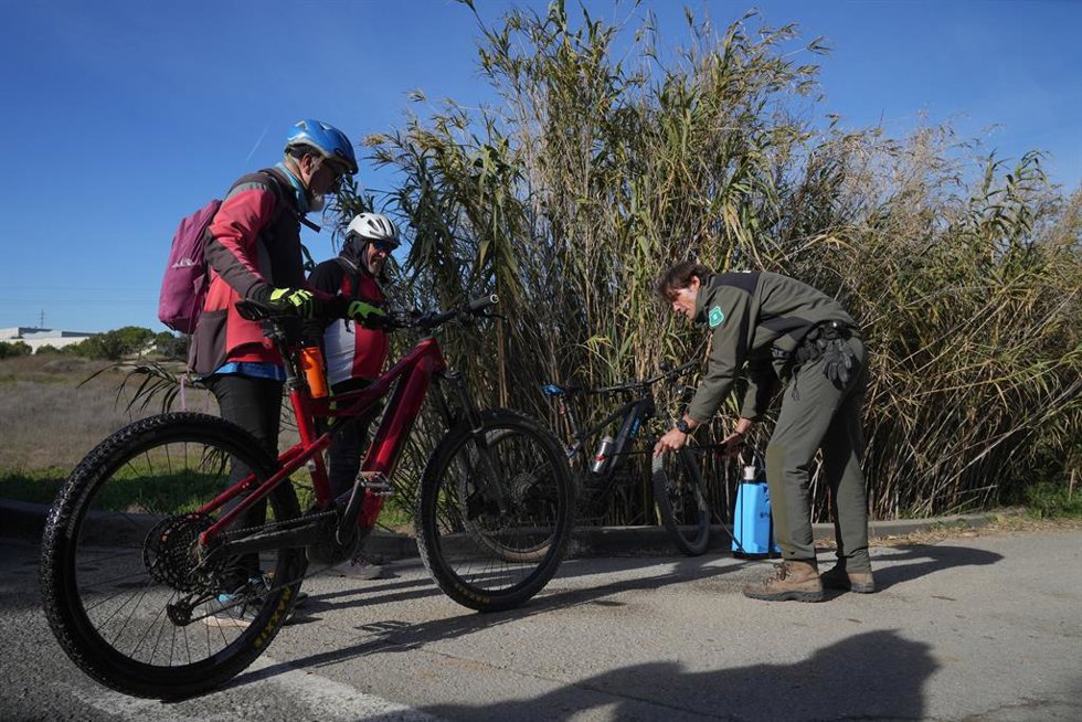 Un agente rural de los Mossos d'Esquadra desinfecta las bicicletas de unos ciclistas en las zonas restringidas por la cuarentena ante la peste porcina africana
