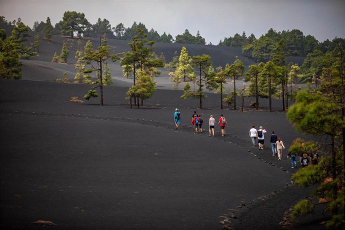 Archivo - Turistas caminan por un sendero afectado por la lava del volcán de Tajogaite, en la Sierra de Cumbre Vieja, La Palma