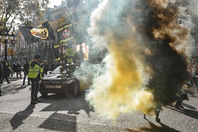Diversos manifestants amb pots de fum durant una marxa lenta de taxistes