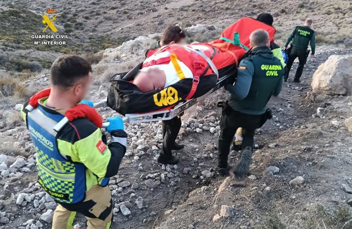 Agentes de la Guardia Civil y bomberos trasladan al senderista herido desde la zona de Loma Pelada, en Cala Higuera-Níjar (Alemría).
