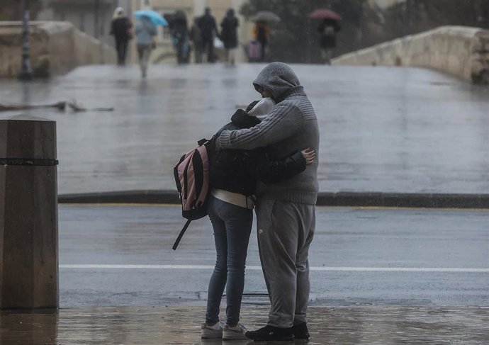 Archivo - Una pareja se abraza mientras llueve en València