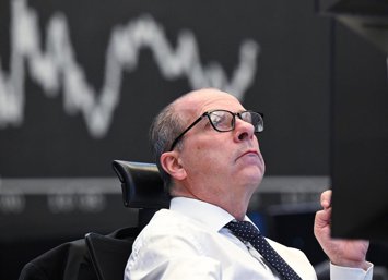 Archivo - 08 April 2025, Hesse, Frankfurt/Main: A trader sits on the trading floor of the Frankfurt Stock Exchange in front of the display board showing the Dax curve. US President Trump's aggressive US tariff policy can also be seen as a trade war agains
