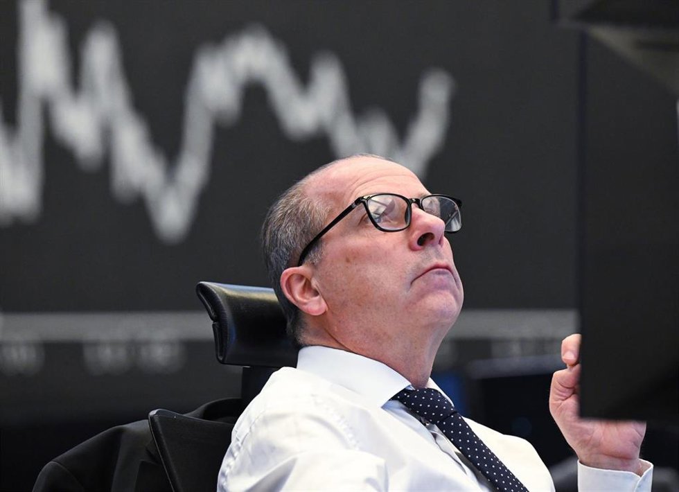 Archivo - 08 April 2025, Hesse, Frankfurt/Main: A trader sits on the trading floor of the Frankfurt Stock Exchange in front of the display board showing the Dax curve. US President Trump's aggressive US tariff policy can also be seen as a trade war agai