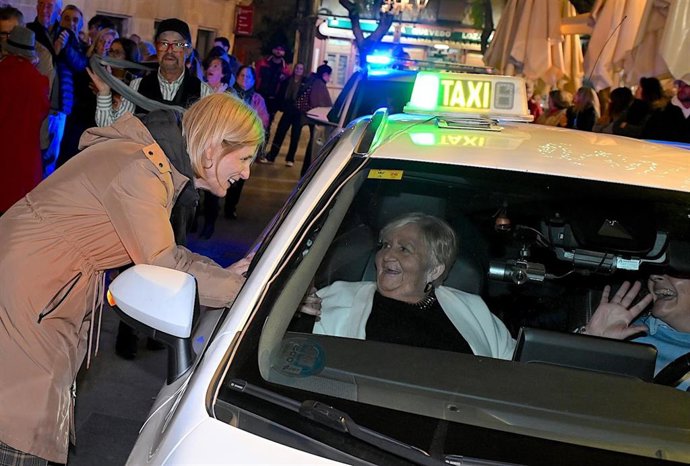 La alcaldesa de Jerez de la Frontera (Cádiz), María José García-Pelayo, saluda a una usuaria de una residencia demayores que participa en la caravana de taxis para ver el alumbrado de Navidad