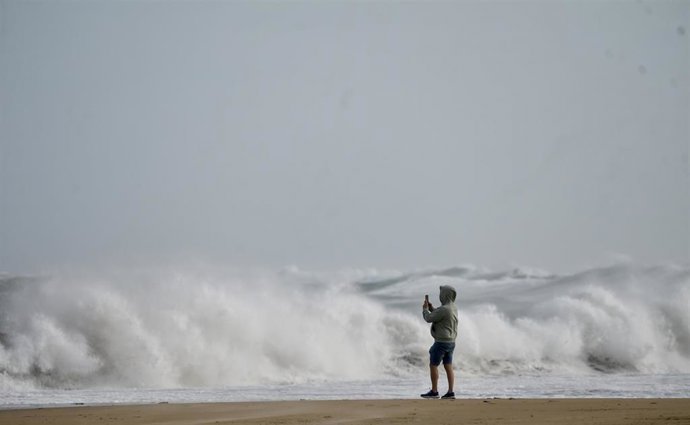 Archivo - Una persona hace fotos del oleaje