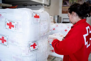 Archivo - Una voluntaria de Cruz Roja Española con una carga de ayuda humanitaria, en una fotografía de archivo.