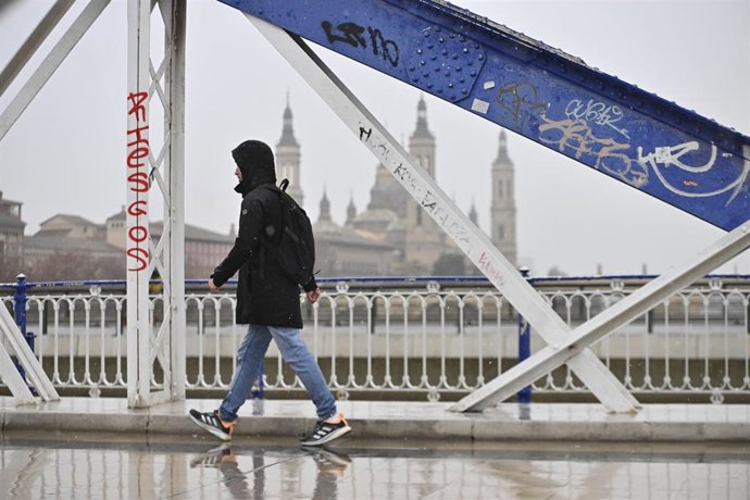 Archivo - Una persona camina por la calle bajo la nieve, a 19 de enero de 2024, en Zaragoza, Aragón (España).