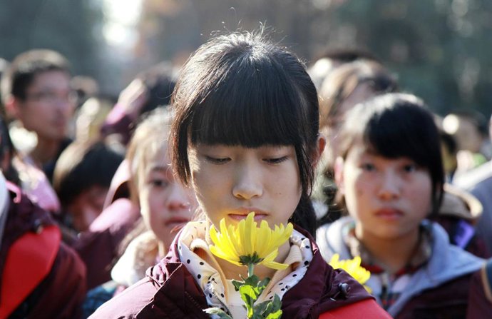 Archivo - Chica rinde homenaje a los fallecidos en la masacre de Nanjing hace 77 años.