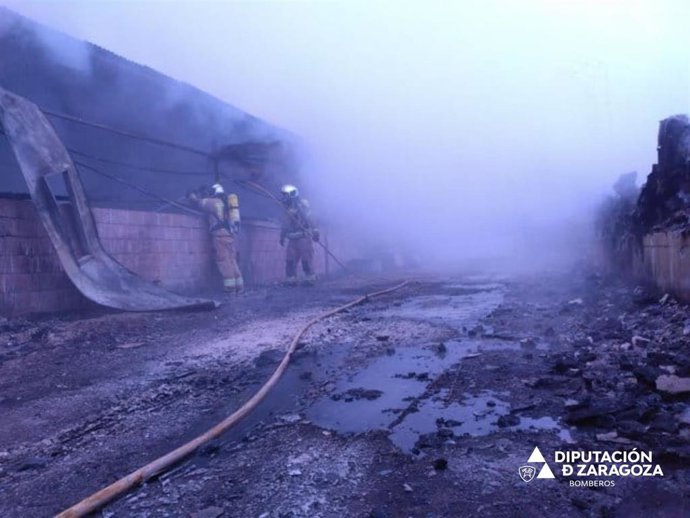 Bomberos de la DPZ trabajan en el incendio de unas naves porcinas en la localidad de Sancho Abarca de Tauste.