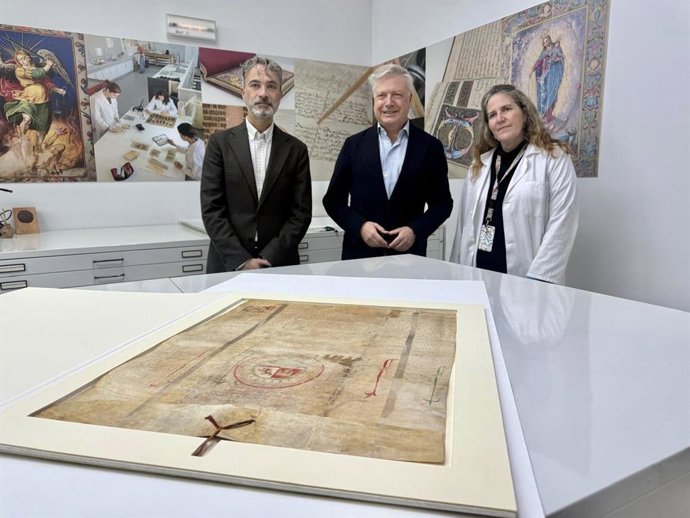 Ignacio Montoro y Primo Jurado, junto a una técnica del IAPH, ante el restaurado 'Privilegio rodado de confirmación de Alfonso XI a favor de Baeza'.