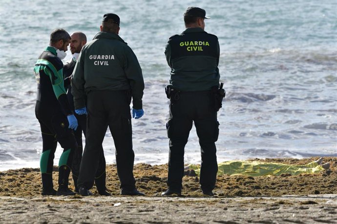 Archivo - Guardias civiles frente a un cadáver de un migrante en la orilla de la playa de la Ribera, a 31 de enero de 2023, en Ceuta (España). 