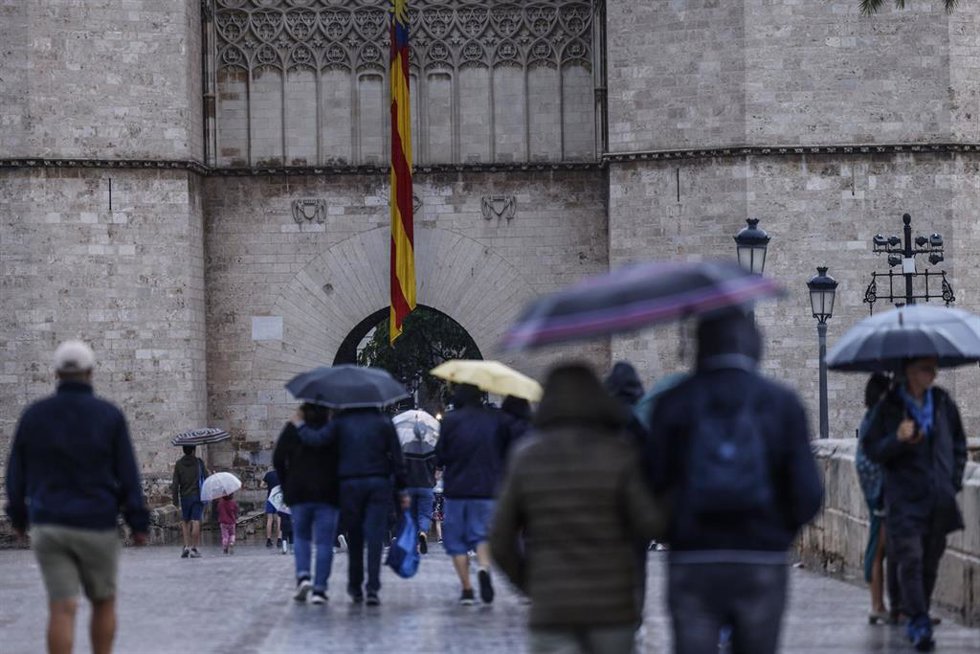 Archivo - Personas se protegen de la lluvia en Valncia en imagen de archivo