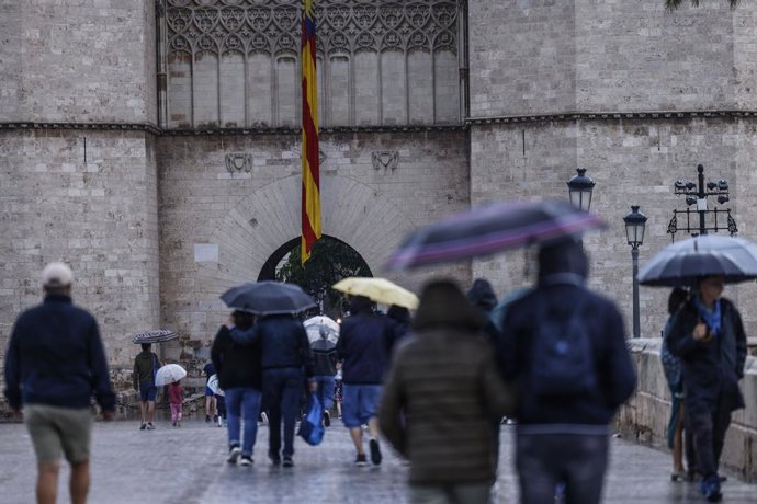 Archivo - Arxiu - Persones es protegeixen de la pluja a València en imatge d'arxiu