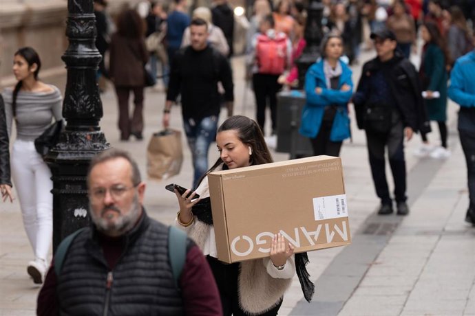 Archivo - Una joven sujeta una caja de una tienda de ropa durante la campaña de Navidad, a 1 de diciembre de 2023, en Barcelona, Catalunya (España)