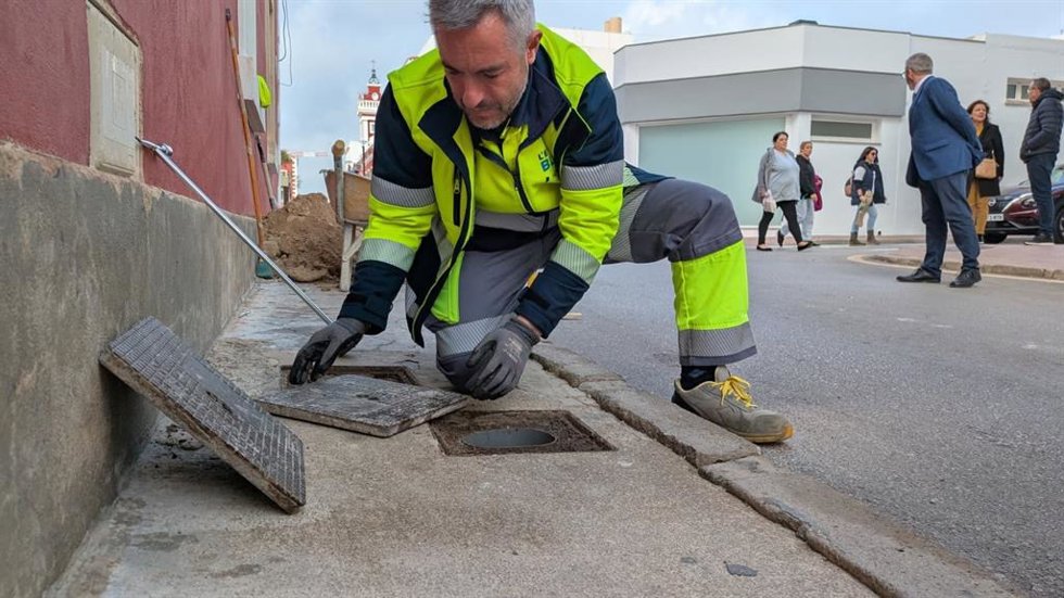 Un empleado levanta una arqueta de la red de suministro de agua.