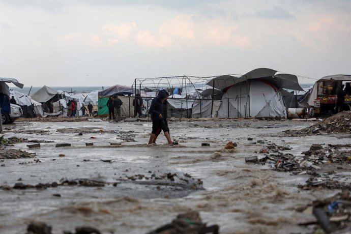 GAZA, 12 de dezembro de 2025 -- Palestinos caminham em uma rua inundada após a chuva na Cidade de Gaza, em 12 de dezembro de 2025. Pelo menos 14 pessoas foram mortas na Faixa de Gaza nas últimas 24 horas, quando casas desabaram e tendas que abrigavam famí