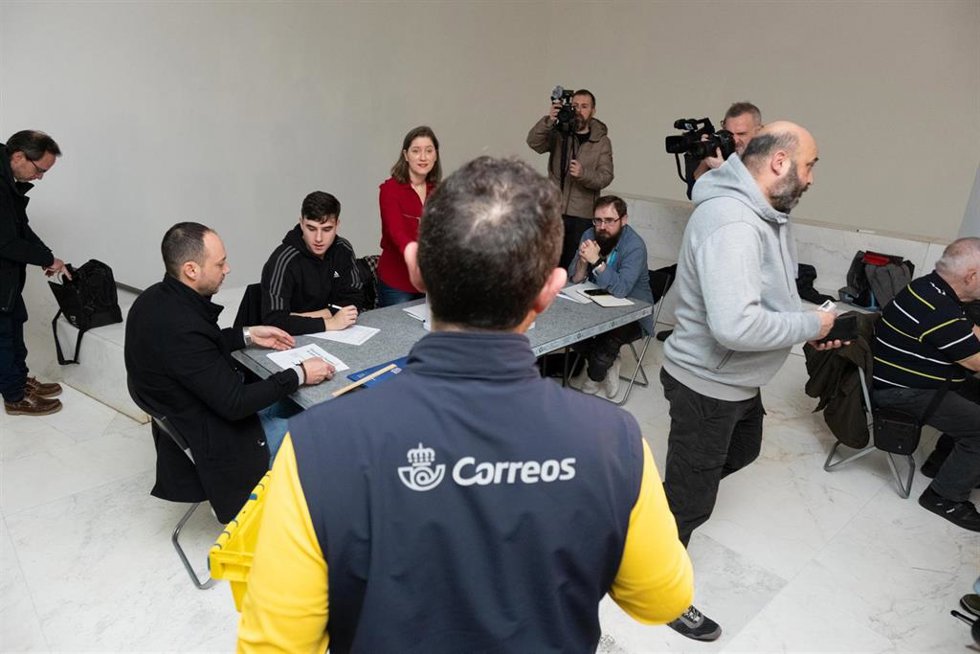 Archivo - Un trabajador de Correos lleva los votos realizados por correo a la mesa electoral en una imagen de achivo