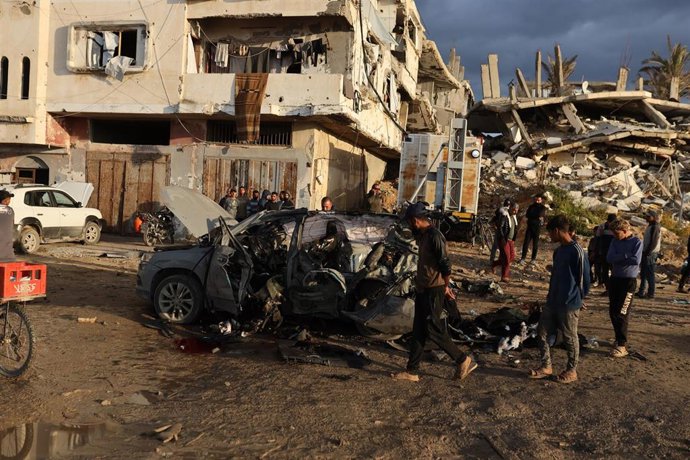 Palestinians inspect the site of an Israeli strike on a car in Gaza City.