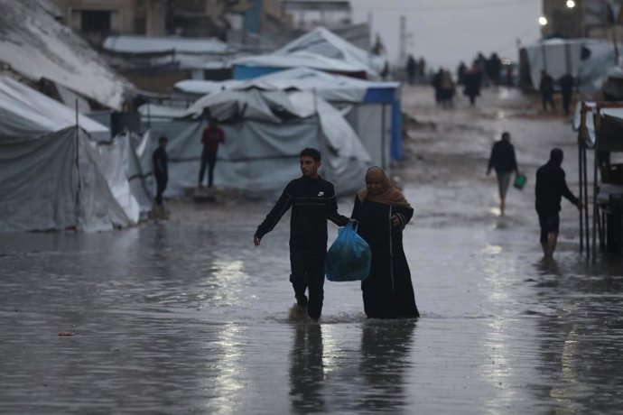 December 16, 2025, Gaza City, Gaza Strip, Palestinian Territory: Palestinians wade during rain fall through flooded streets in Gaza City, whose infrastructure was severely damaged in the recent Israeli war. A rainstorm that struck the Gaza Strip this week