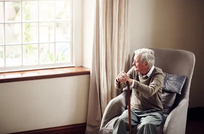 Anciano sentado mirando por la ventana. - KUPICOO/ISTOCK - Archivo