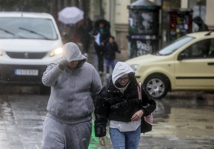 Archivo - Dos personas se tapan la cabeza con la capucha de la chaqueta como consecuencia de la lluvia, a 6 de febrero de 2023, en Valencia, Comunidad Valenciana (España). 