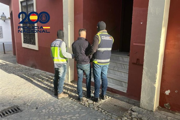 Dos agentes de la Policía Nacional escoltan a un detenido por la presunta muerte violenta de un vecino de Jerez de 77 años de edad con quien había mantenido una discusión en el interior del domicilio de la víctima.
