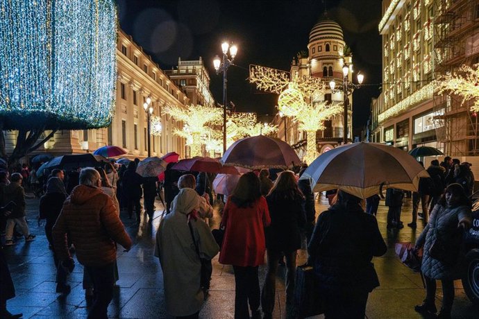 Numeroso público con paraguas en la Avenida de la Constitución contemplando la iluminación navideña de la ciudad, a 16 de diciembre de 2025, en Sevilla (España). 