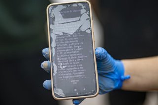 Archivo - Una mujer muestra la alerta de Protección Civil en su teléfono móvil en La Ràpita (Tarragona)