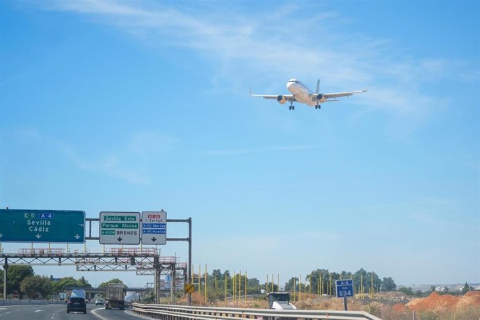 Archivo - Un avión sobrevuela la autovía A-4 antes de aterrizar en el aeropuerto de Sevilla.