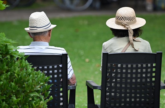 Archivo - FILED - 15 July 2025, Rhineland-Palatinate, Bad Kreuznach: An elderly couple listens to a school orchestra concert in the Kurpark. The average retirement age in Germany continued to rise last year, with people stopping work at an average age of 