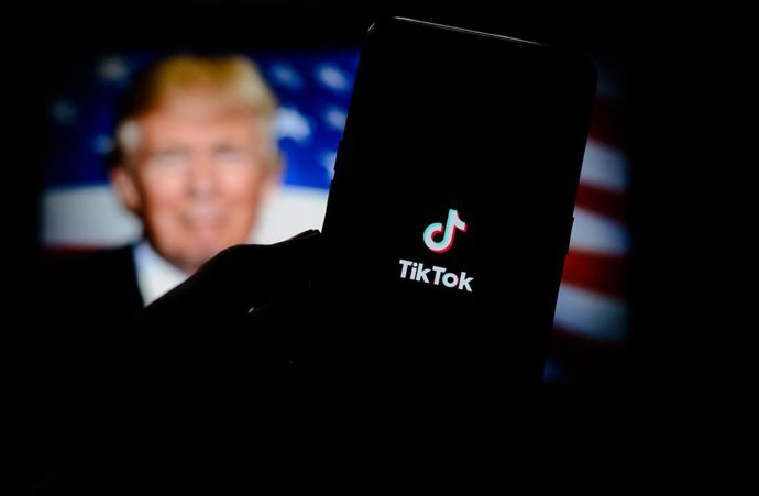 Archivo - Composición de imagen con el logotipo de TikTok en un teléfono móvil con una bandera estadounidense y un retrato del presidente de EEUU, Donald Trump, de fondo