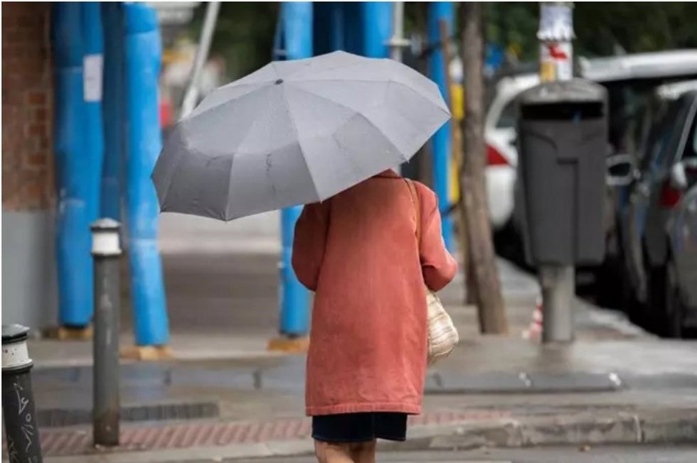 Archivo - Una mujer pasea por una calle con un paraguas.