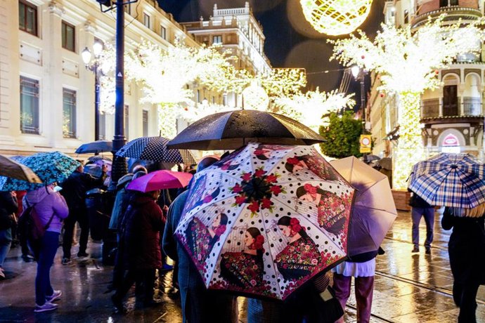 Numeroso público con paraguas en la Avenida de la Constitución contemplando la iluminación navideña de la ciudad, a 16 de diciembre de 2025, en Sevilla (España). 