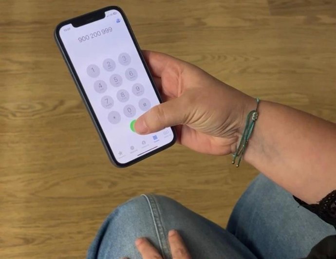 Una mujer llama al teléfono 900 200 999.