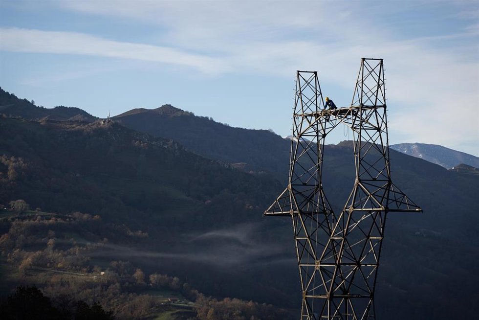 Una persona trabaja subida a una torre de alta tensión