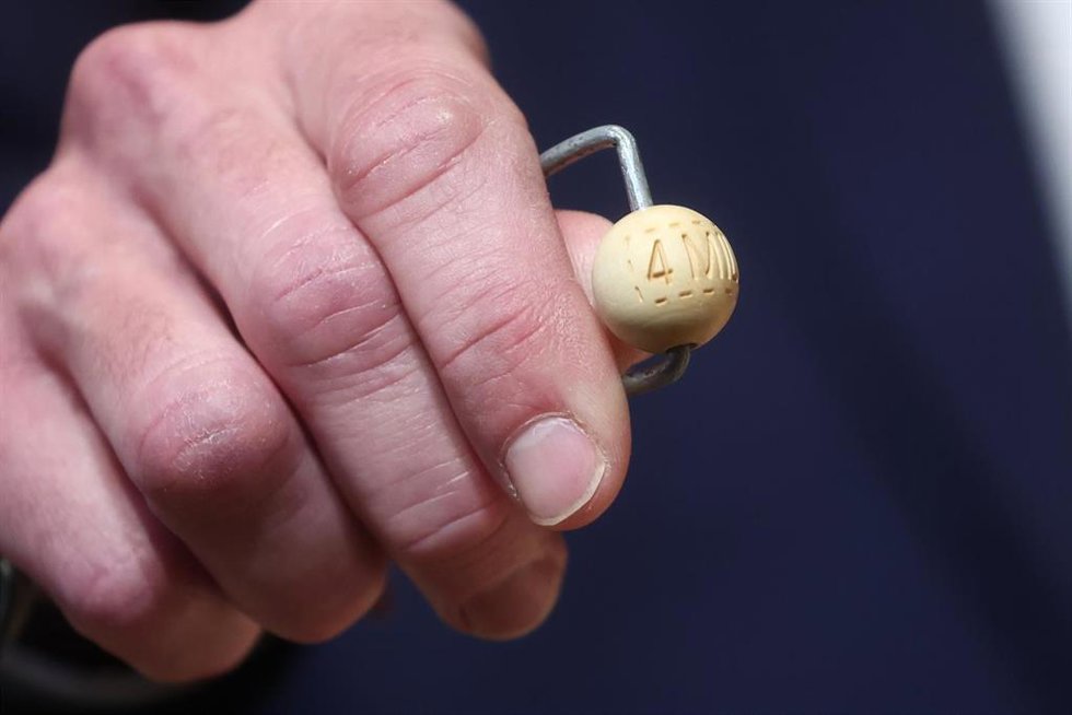 Un hombre mete las bolas con los premios en el bombo de la lotería